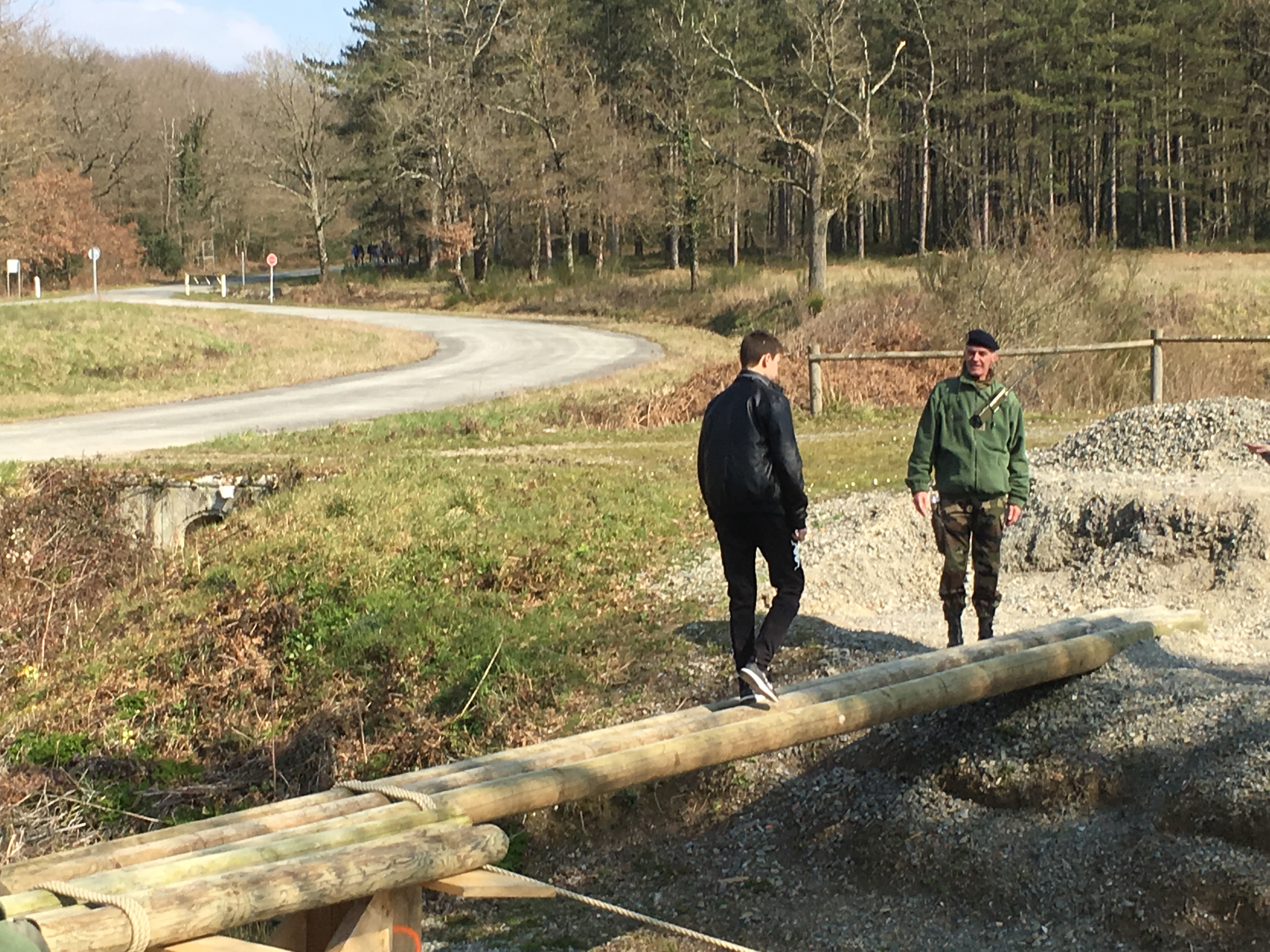 ranchissement d’un fossé par un élève du collège Montaigne sur un pont réalisé avec des rondins en bois.
